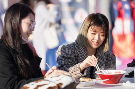 (miniature) Deux jeunes femmes mangent dans un marché installé pour célébrer le Nouvel An chinois dans le parc Ueno à Tokyo