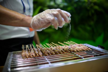 (miniature) Un employé fait griller des brochettes d'agneau lors de la 8e Exposition Chine-Eurasie à Urumqi