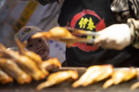 (miniature) Un enfant attend ce qu'il a command&eacute; &agrave; manger dans un march&eacute; de nuit &agrave; Yichun