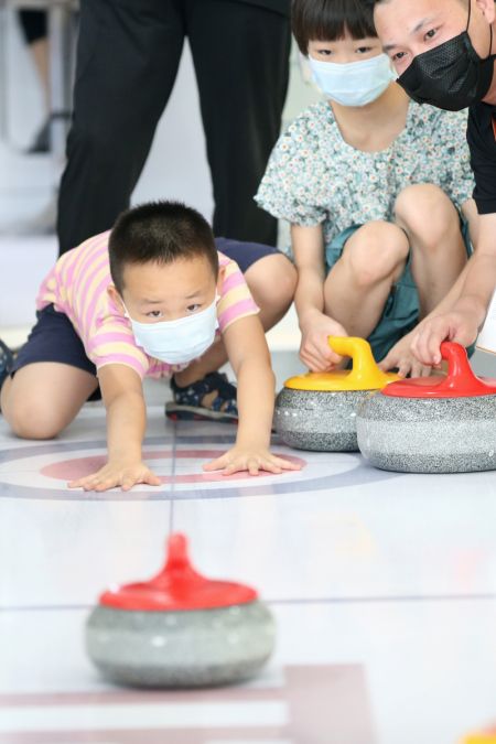 (miniature) Un garçon pratique le curling dans l'espace d'exposition des sports d'hiver du monde du Salon international du commerce des services de Chine 2020