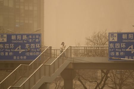 (miniature) Photo montrant une femme portant un masque marchant dans la tempête de sable à Beijing