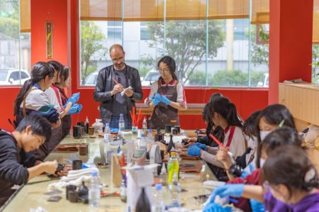 (miniature) L'artiste français Vincent Cazeneuve enseigne l'art de la laque à des élèves dans un centre de formation professionnelle du district de Chengkou