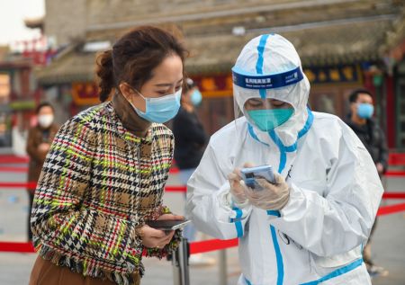 (miniature) Une membre du personnel m&eacute;dical aide une habitante &agrave; enregistrer ses informations personnelles pour un test d'acide nucl&eacute;ique &agrave; Hohhot