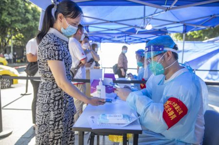 (miniature) Un professionnel de santé enregistre les informations d'une habitante pour un test d'acide nucléique dans le Nouvel Arrondissement de Liangjiang