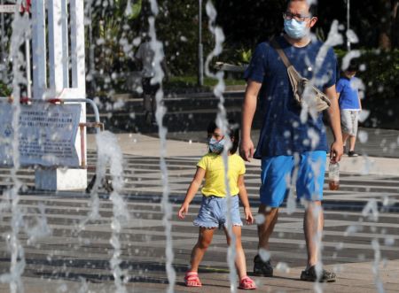 (miniature) Des gens passent devant une fontaine lors d'une journée chaude d'été