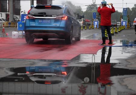 (miniature) Un membre du personnel désinfecte une voiture sortant du marché Xinfadi