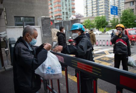 (miniature) Un habitant reçoit une livraison au portail d'un quartier résidentiel de l'arrondissement de Chaoyang