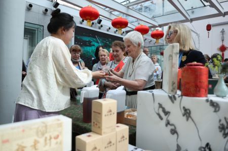 (miniature) Une femme reçoit une tasse de thé chinois lors du Salon culturel Yaji à Bruxelles