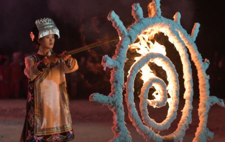 (miniature) Une porteuse de torche allume un anneau de feu lors de la fête annuelle des Torches de l'ethnie Yi dans le district de Weining de la province chinoise du Guizhou (sud-ouest)