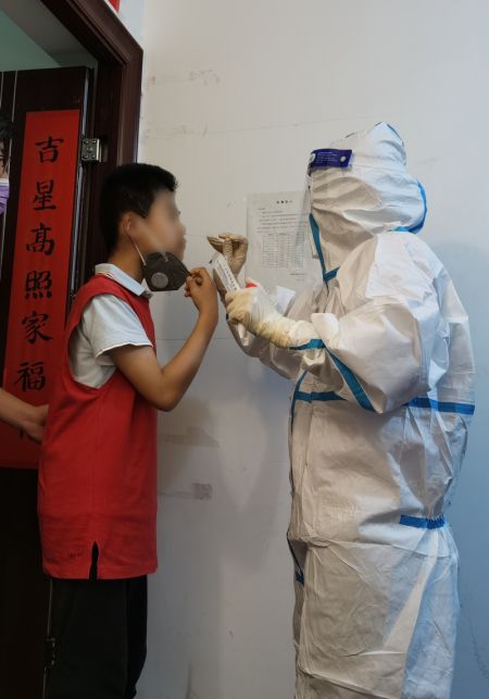 (miniature) Un professionnel de santé prélève un échantillon sur un habitant pour un test d'acide nucléique dans un quartier résidentiel de l'arrondissement de Haidian