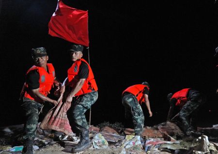 (miniature) Des policiers arm&eacute;s transportent des sacs de sable sur une digue &agrave; Poyang