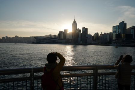(miniature) Des gens admirent le lever du soleil dans le port de Victoria à Hong Kong