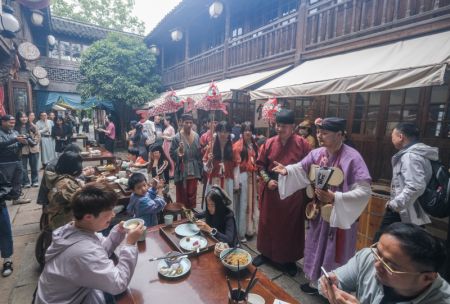 (miniature) Des employés vêtus de costumes traditionnels discutent avec des visiteurs dans le Puyuan Fashion Resort