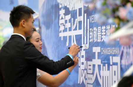 (miniature) Un couple ayant particip&eacute; &agrave; la lutte contre le COVID-signe une affiche lors d'un mariage de groupe organis&eacute; par le comit&eacute; de gestion du mont Changbai