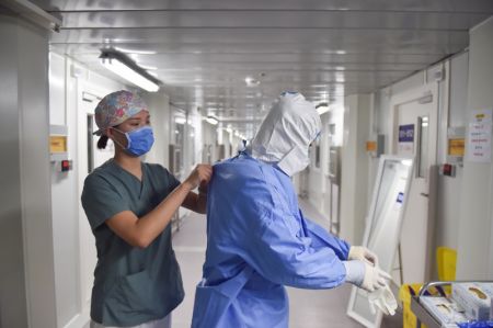 (miniature) Une infirmière aide son collègue à enfiler une combinaison de protection à l'extérieur d'une salle d'isolement à l'hôpital de Ditan à Beijing