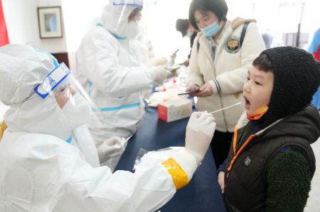 (miniature) Une professionnelle de la sant&eacute; pr&eacute;l&egrave;ve un &eacute;chantillon sur &eacute;couvillon &agrave; un enfant dans un site de tests d'acide nucl&eacute;ique de l'arrondissement de Xiangfang