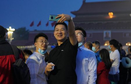 (miniature) Des gens prennent un selfie avant la c&eacute;r&eacute;monie de lever du drapeau national sur la place Tian'anmen