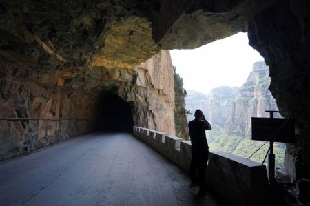 (miniature) Un touriste prend des photos sur une route creus&eacute;e dans une falaise dans le district de Pingshun