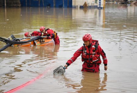 (miniature) Un secouriste enl&egrave;ve des d&eacute;chets autour de pompes lors d'op&eacute;rations de drainage dans le centre-ville de Zhuozhou de la province chinoise du Hebei (nord)