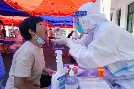 (miniature) Un professionnel de la santé prélève un échantillon par écouvillon sur une habitante dans un site de test d'acide nucléique de la COVID-19 de l'arrondissement de Guangling