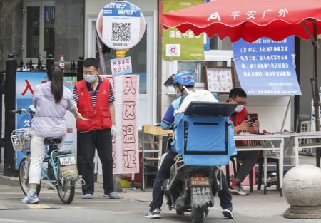 (miniature) Un membre du personnel d'un quartier résidentiel vérifie la température corporelle d'une habitante à l'entrée d'une résidence dans l'arrondissement de Xicheng à Beijing