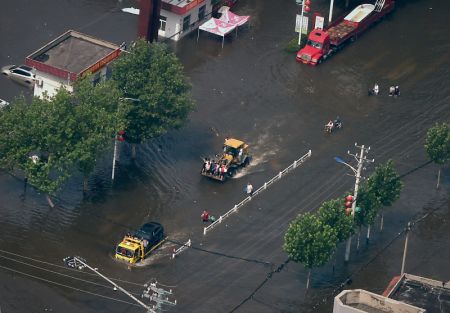 (miniature) Des camions et une pelleteuse évacuent des habitants dans la ville inondée de Weihui au Henan