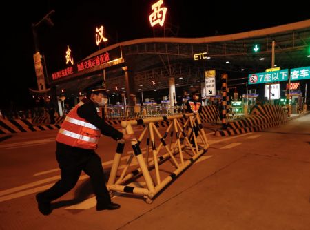 (miniature) Un membre du personnel retire une barrière près d'une station de péage d'autoroute dans l'ouest de Wuhan