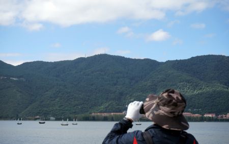 (miniature) Un homme regarde avec une paire de jumelles le paysage du lac Dianchi