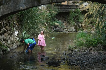 (miniature) Une fille attrape du poisson avec son père dans un ruisseau