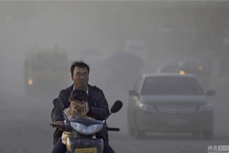 (miniature) père chinois et son fils sur un scooter dans la pollution