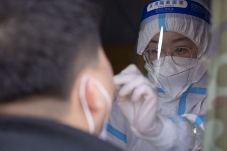 (miniature) Une professionnelle de la sant&eacute; pr&eacute;l&egrave;ve un &eacute;chantillon sur &eacute;couvillon &agrave; un habitant dans un site de tests d'acide nucl&eacute;ique de l'arrondissement de Daoli
