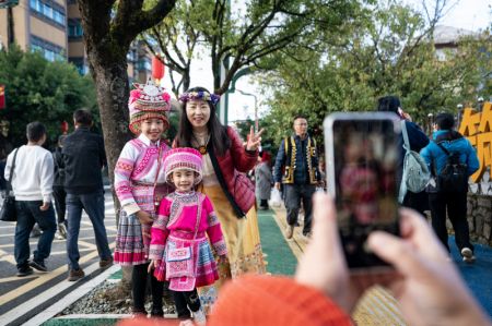 (miniature) Une touriste pose pour une photo avec des enfants locaux lors d'un festival de tourisme culturel dans le district de Luchun de la préfecture autonome Hani et Yi de Honghe