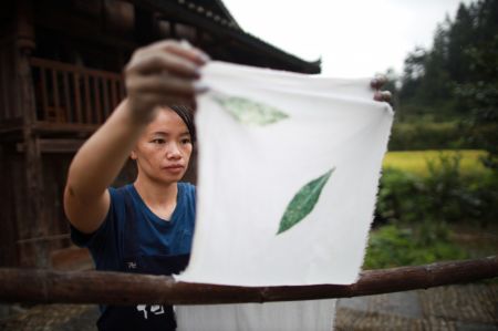 (miniature) Une femme fait sécher des étoffes dans un atelier du village Dong de Fengdeng