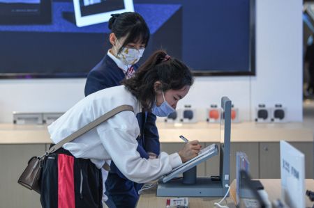 (miniature) Une consommatrice teste un appareil électronique durant les congés de la fête du Printemps dans un centre commercial hors taxes à Haikou