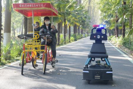 (miniature) Un touriste prend en photo un véhicule de patrouille sans conducteur dans le parc forestier national de Binhu