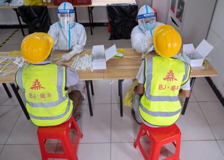 (miniature) Des professionnels de santé effectuent des prélèvements de gorge sur des ouvriers de construction dans un site de prélèvement temporaire dans l'arrondissement de Daxing