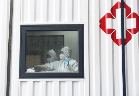 (miniature) Des membres du personnel médical mettent leur équipement de protection individuelle dans un laboratoire temporaire pour des tests d'acide nucléique sur la place de la gare de Nanjing