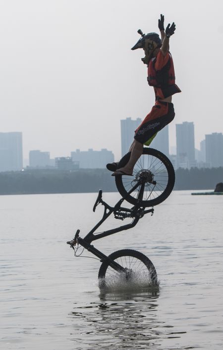 (miniature) Un cycliste saute dans le lac de l'Est lors d'un festival annuel de saut en BMX à Wuhan