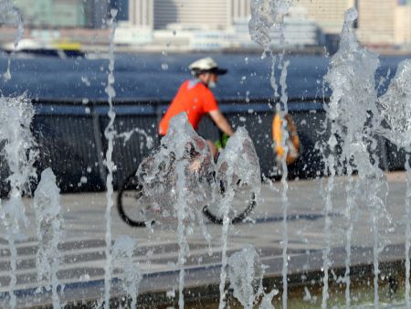 (miniature) Un habitant passe à vélo devant une fontaine lors d'une journée chaude d'été