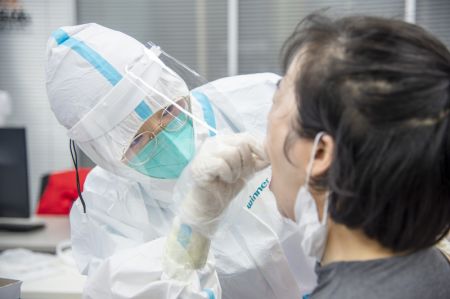 (miniature) Un professionnel de la santé prélève un échantillon de gorge sur une résidente pour le test d'acide nucléique de la COVID-19 à Wuhan