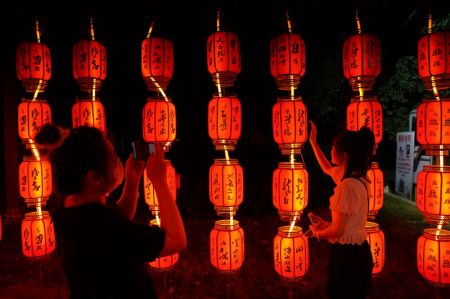(miniature) Une visiteuse pose pour une photo avec les installations lumineuses de la fête de la mi-automne au site touristique du pavillon Tengwang