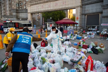(miniature) Un livreur remet les produits d'un client &agrave; un membre du personnel de pr&eacute;vention et de contr&ocirc;le de l'&eacute;pid&eacute;mie dans le quartier r&eacute;sidentiel de Hongfuyuan