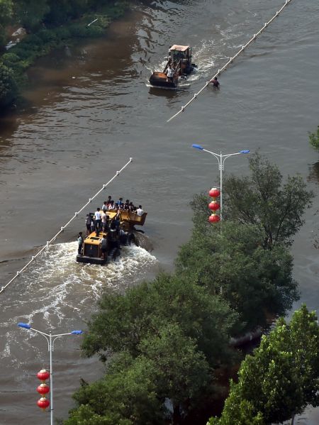 (miniature) Un camion et une pelleteuse évacuent des habitants dans la ville inondée de Weihui au Henan