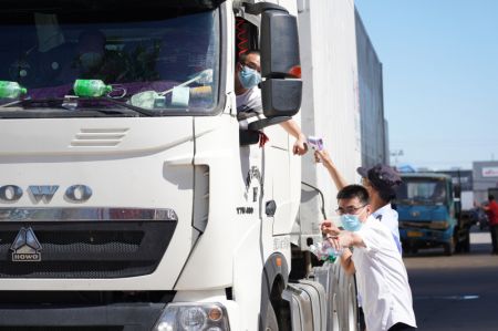 (miniature) Un employé prend la température corporelle d'un chauffeur de camion pendant que son collègue lui indique la direction à suivre pour se garer sur l'un des cinq sites de commerce provisoire désignés à la suite de la suspension du marché de gros de Xinfadi