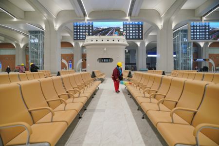 (miniature) Un ouvrier nettoie les chaises d'une salle d'attente de la gare de Xiongan