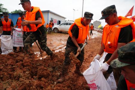 (miniature) Des membres de la police armée emballent du sable pour renforcer une digue dans le district de Poyang de la province chinoise du Jiangxi (est)