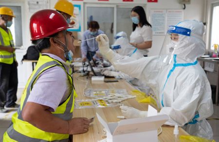 (miniature) Des professionnels de santé effectuent des prélèvements de gorge sur des ouvriers de construction dans un site de prélèvement temporaire dans l'arrondissement de Daxing