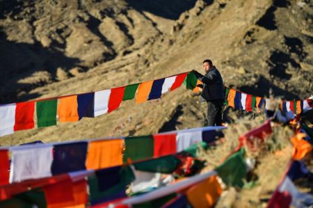 (miniature) Un homme accroche des drapeaux de prières sur une montagne à Xigaze