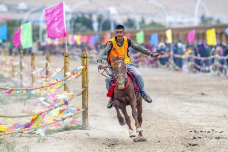 (miniature) Un jeune homme participe à une course de chevaux pendant la fête des bateaux-dragons dans un parc d'exposition du patrimoine culturel immatériel du district autonome tadjik de Taxkorgan