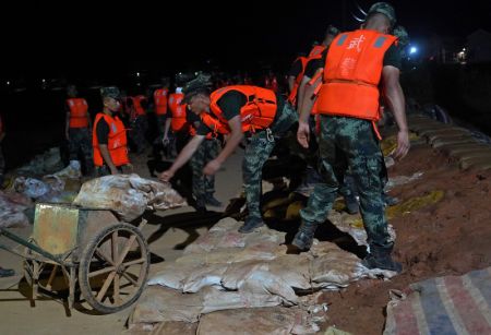 (miniature) Des policiers arm&eacute;s transportent des sacs de sable sur une digue &agrave; Poyang